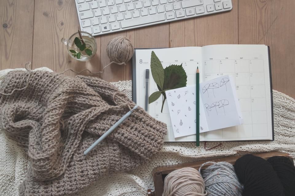 A cozy craft flatlay with knitted fabric, yarn and a notebook