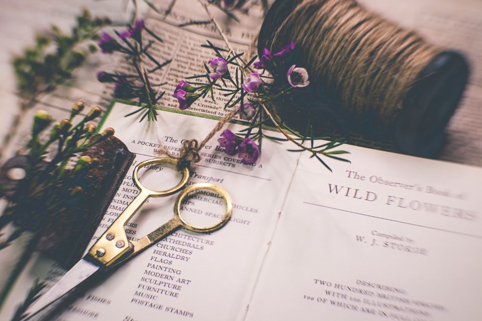 Fabric scissors, thread and flowers on an open book