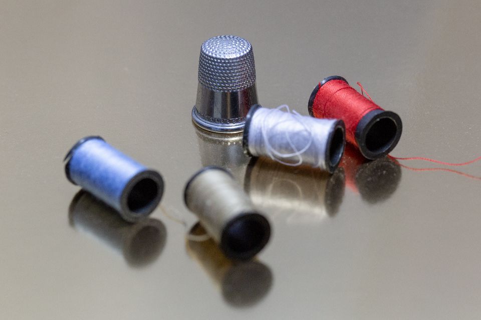 A thimble beside colorful spools of sewing thread