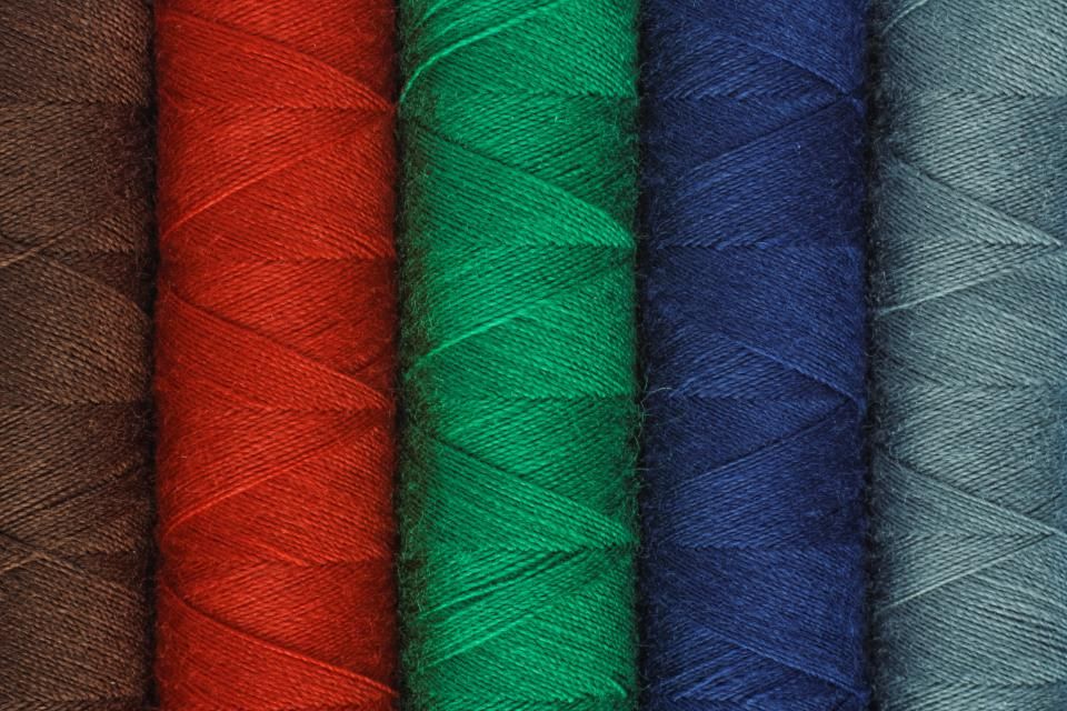 A row of red, green, blue and grey thread spools